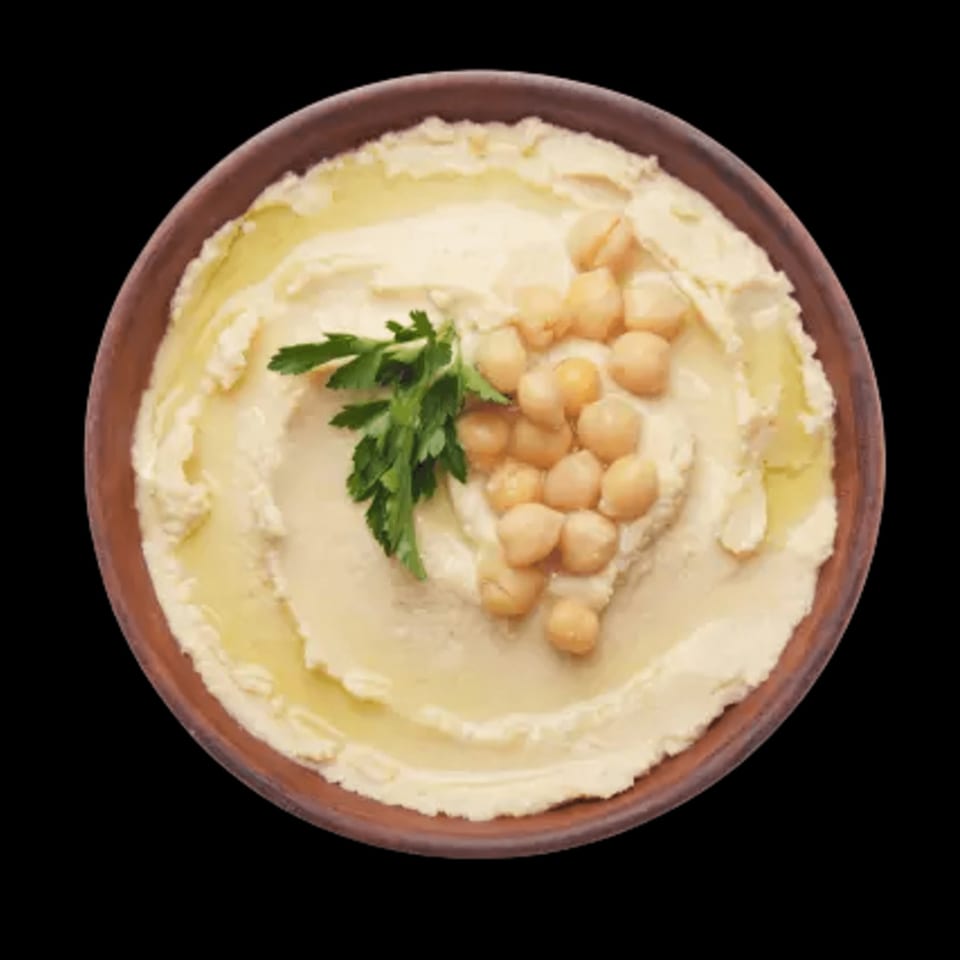 Creamy hummus in a brown bowl, garnished with chickpeas, olive oil, and fresh parsley.