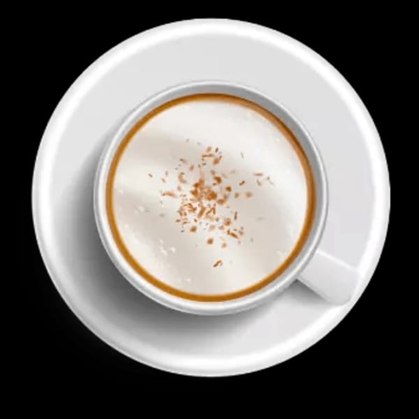 Overhead view of a white cup of coffee with foamed milk and a sprinkle of cinnamon.