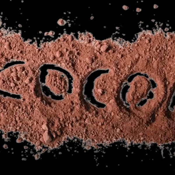 The word "COCOA" spelled out in cocoa powder on a black background.