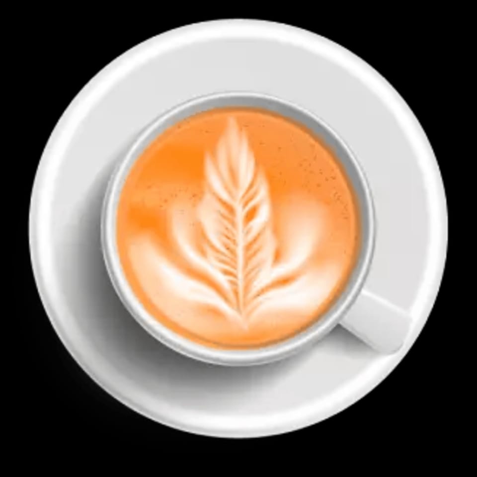 Overhead view of a latte with intricate leaf-shaped latte art in a white cup and saucer.